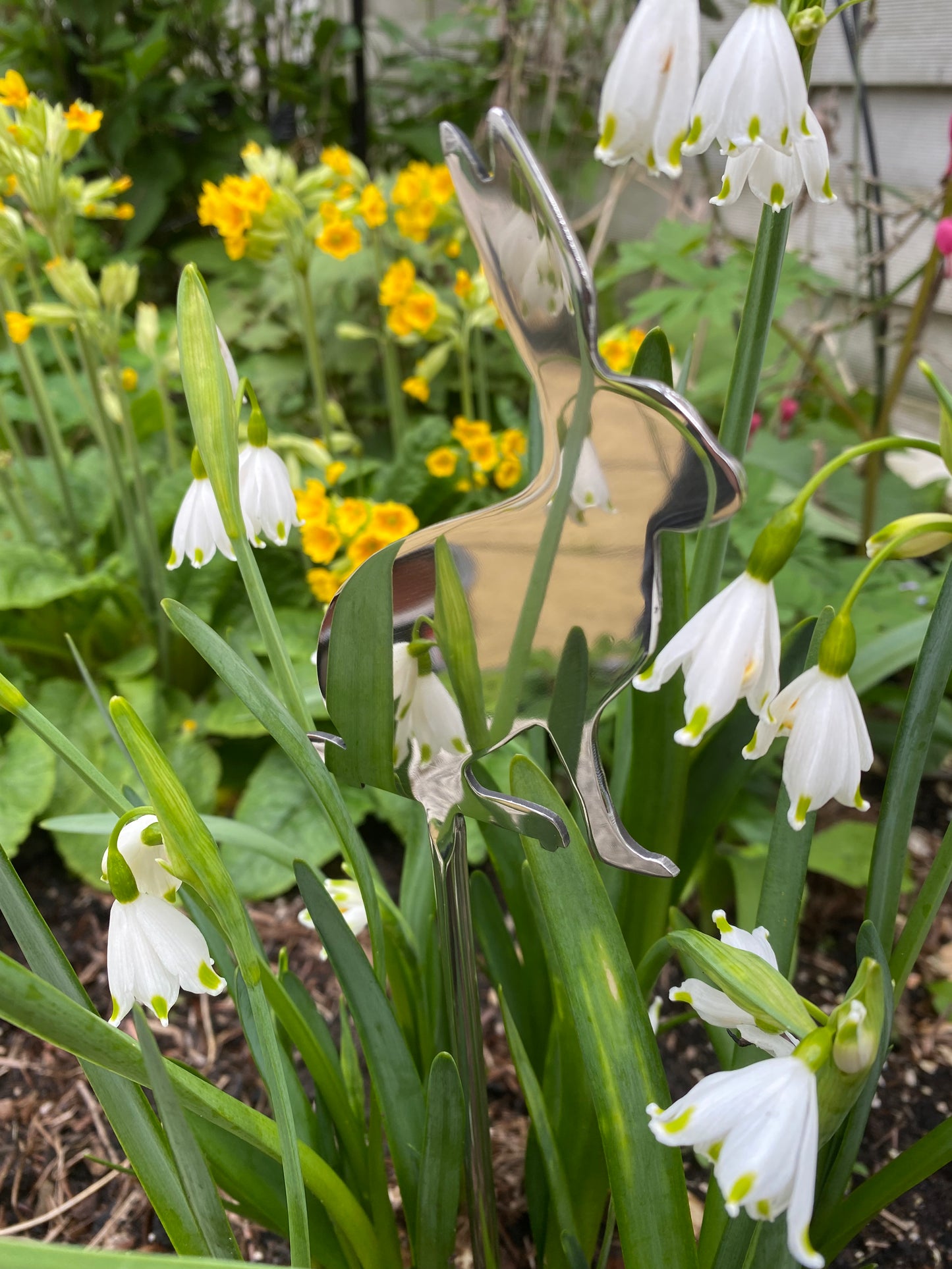Metal butterfly sculpture among snowdrop flowers in a garden