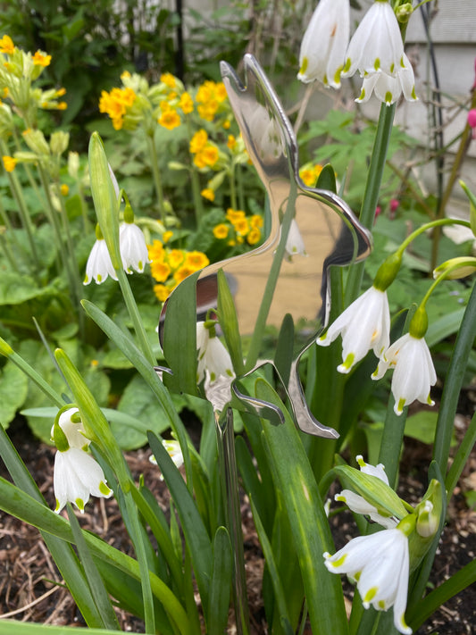 Metal butterfly sculpture among snowdrop flowers in a garden