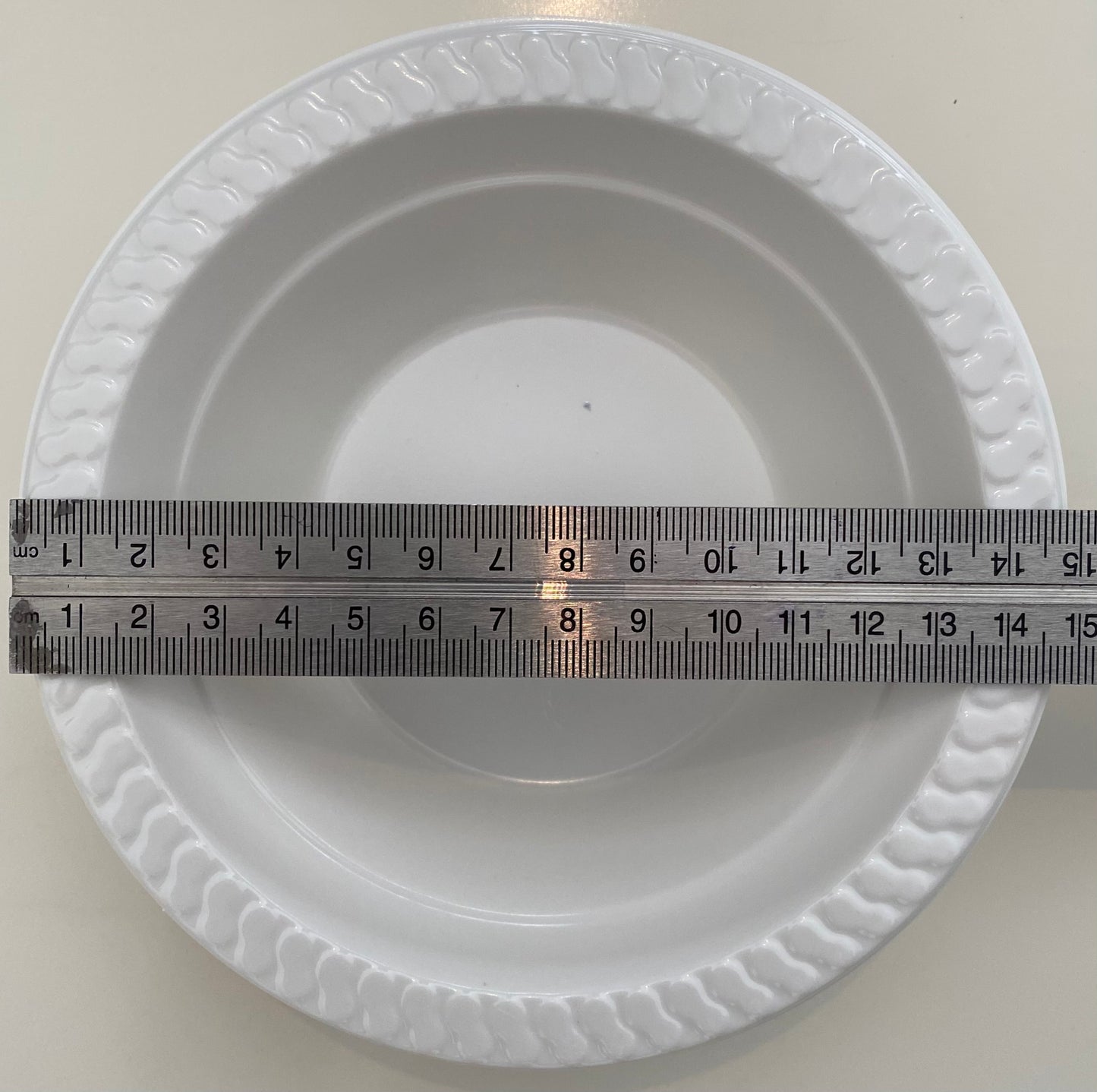White pan trap pan bowl with a ruler for scale on a white background