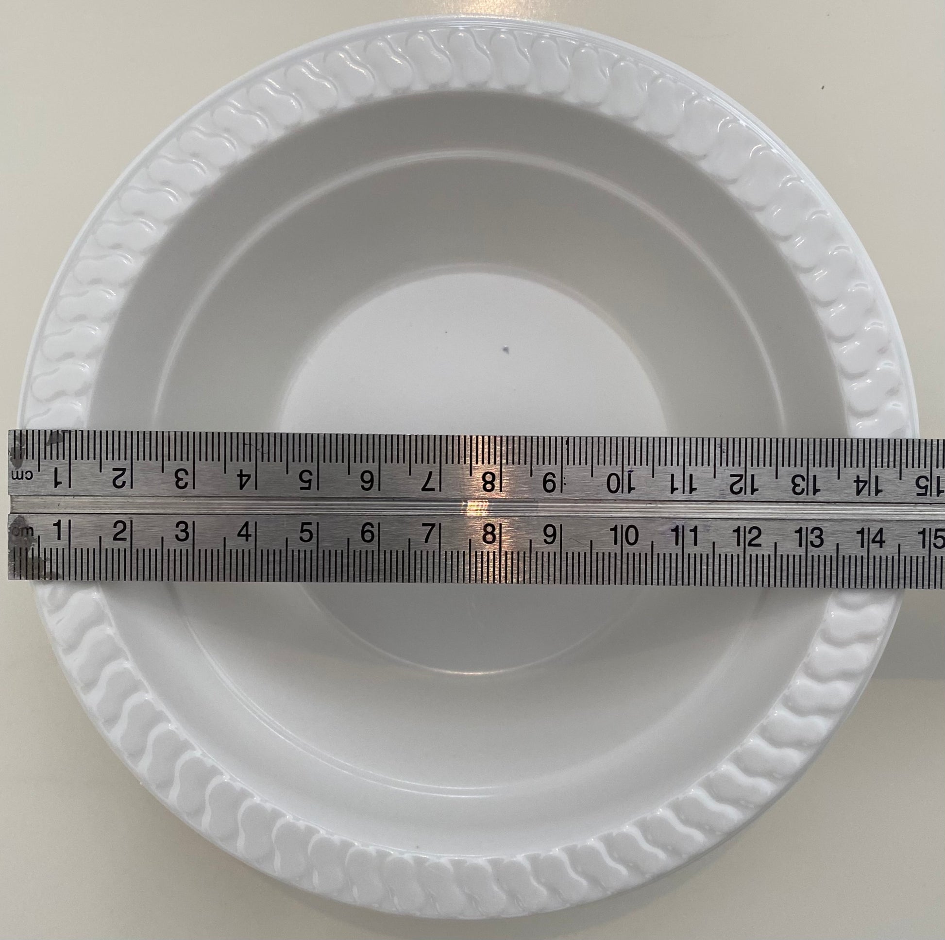 White pan trap pan bowl with a ruler for scale on a white background