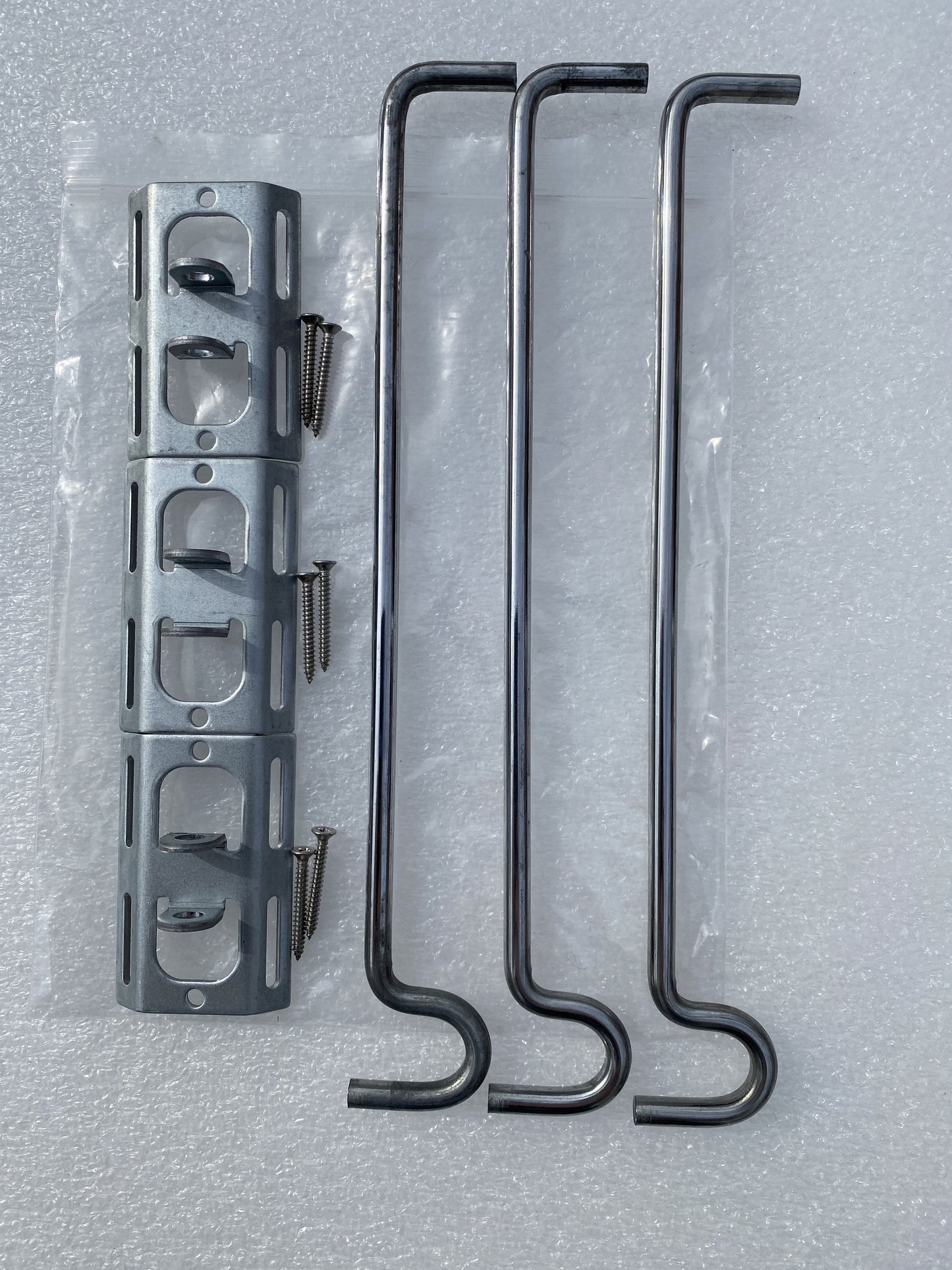 Image shows pack contents for potmagic 3-pack bird feeder hanger bracket set. Pack includes 3 bird feeder hanger bars, 3 brackets and 6 screws. Hanger bar has a deep hooked end to securely retain a bird feeder, etc. Purchased in a 3 pack for £6.99 from potmagic.co.uk. Can be quickly screw fitted to fences, pergolas and walls with screw fittings provided. Brackets are made from strong galvanised steel. Hook-ended hanger bar is made from strong 6mm diameter shiny galvanised steel and are approx 210mm long.