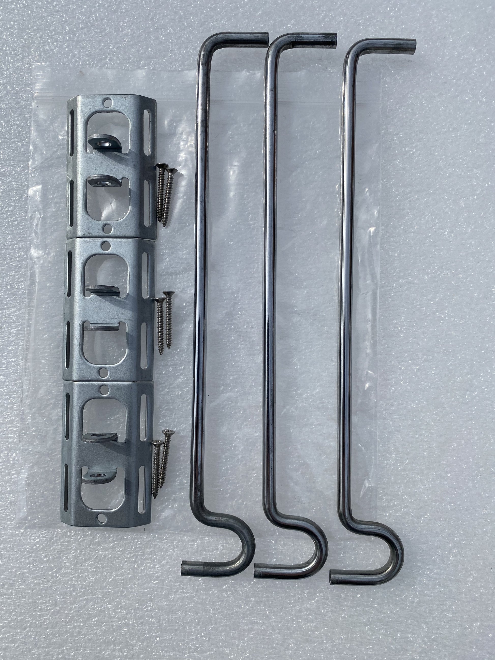 Image shows pack contents for potmagic 3-pack bird feeder hanger bracket set. Pack includes 3 bird feeder hanger bars, 3 brackets and 6 screws. Hanger bar has a deep hooked end to securely retain a bird feeder, etc. Purchased in a 3 pack for £6.99 from potmagic.co.uk. Can be quickly screw fitted to fences, pergolas and walls with screw fittings provided. Brackets are made from strong galvanised steel. Hook-ended hanger bar is made from strong 6mm diameter shiny galvanised steel and are approx 210mm long.